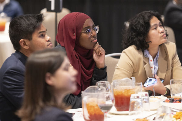 Four people sitting at a table listening to a presentation.
